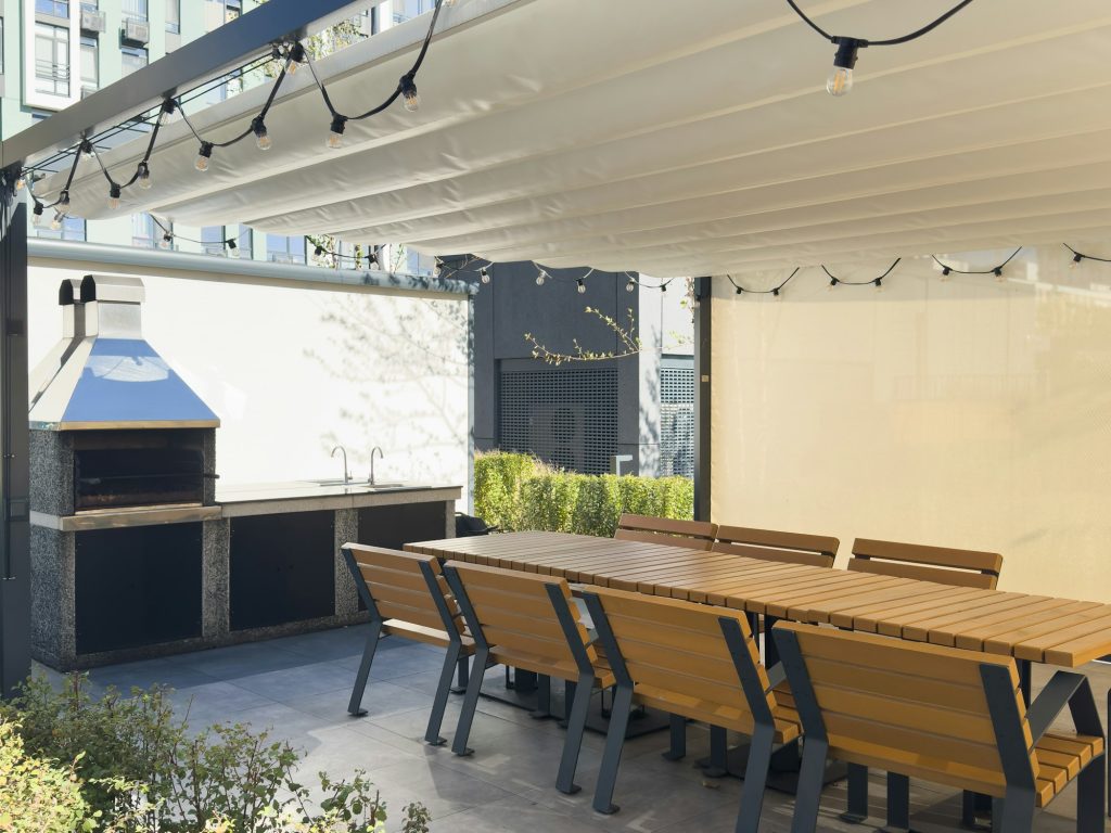 A spacious barbecue area with a canopy made from natural materials, enclosed. A patio with a table