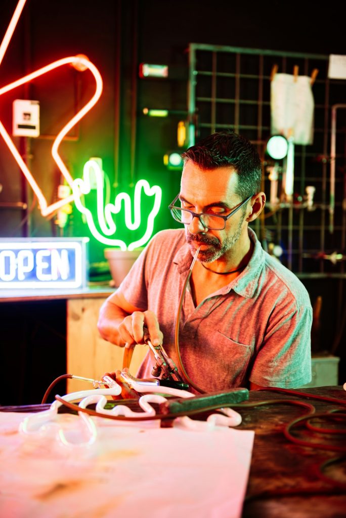 Focused man working on neon signboard at shop