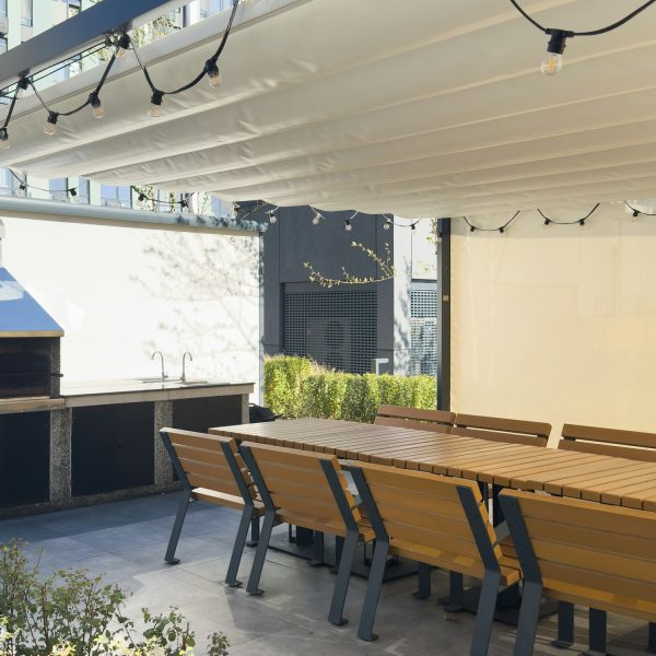 A spacious barbecue area with a canopy made from natural materials, enclosed. A patio with a table