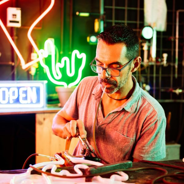 Focused man working on neon signboard at shop